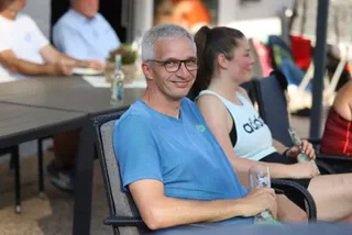 Zuschauende sitzen im Schatten am Spielfeldrand