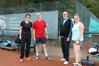 Vier Mitglieder vor der Werbebande am Platz