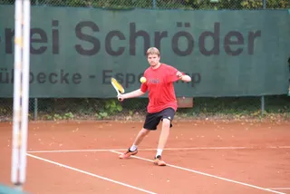 Ein Junge im roten Trikot beim Aufschlag