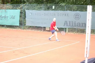 Weiter Blick über den Platz auf einen Spieler an der Grundlinie