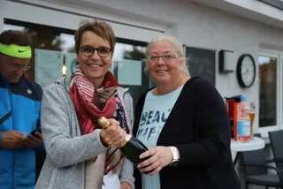 Zwei Mitglieder mit einer Flasche Sekt bei der Siegerehrung