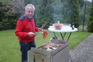 Ein Mitglied wendet Fleisch auf dem Grill
