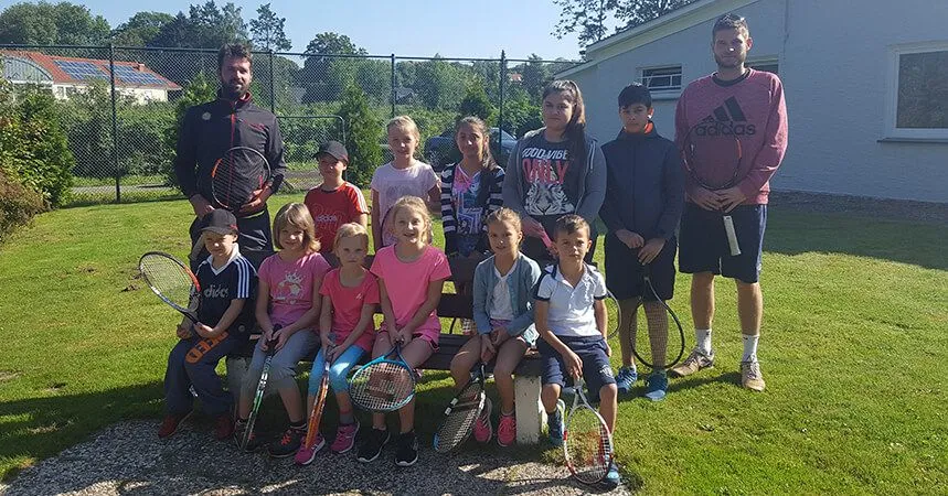 Kinder bei den Ferienspielen mit ihrem Trainer auf der Wiese