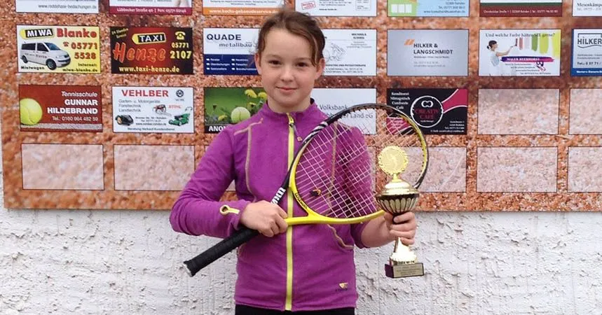 Clara Düning mit Pokal und Schläger vor der Sponsorenwand
