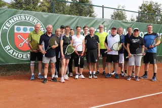 Die Mitglieder mit Schlägern vor dem Vereinsbanner
