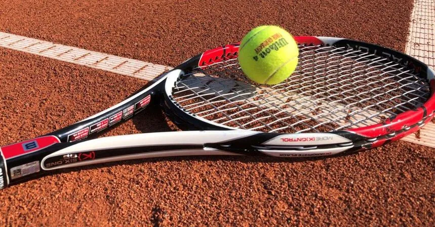 Ein Tennisschläger mit Ball auf dem Sandplatz